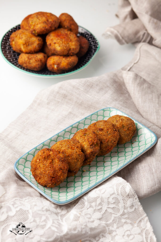 Polpette di patate e ‘nduja croccanti fuori e morbide dentro, servite su un piatto rustico con un tocco di prezzemolo, ricetta calabrese tradizionale e sfiziosa.