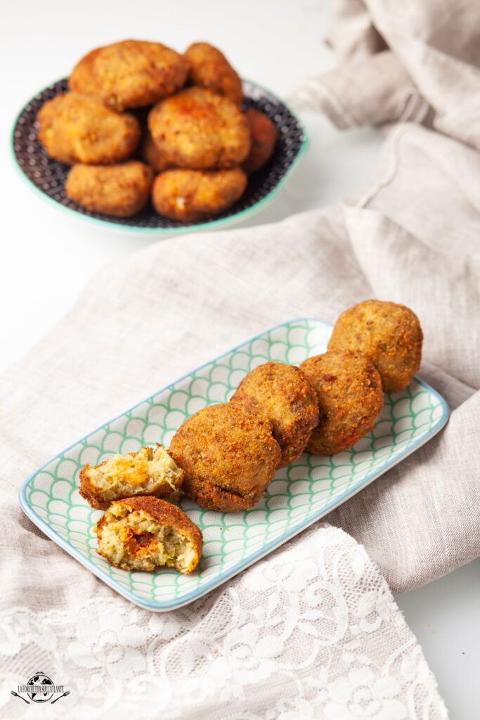 Polpette di patate e ‘nduja croccanti fuori e morbide dentro, servite su un piatto rustico con un tocco di prezzemolo, ricetta calabrese tradizionale e sfiziosa.