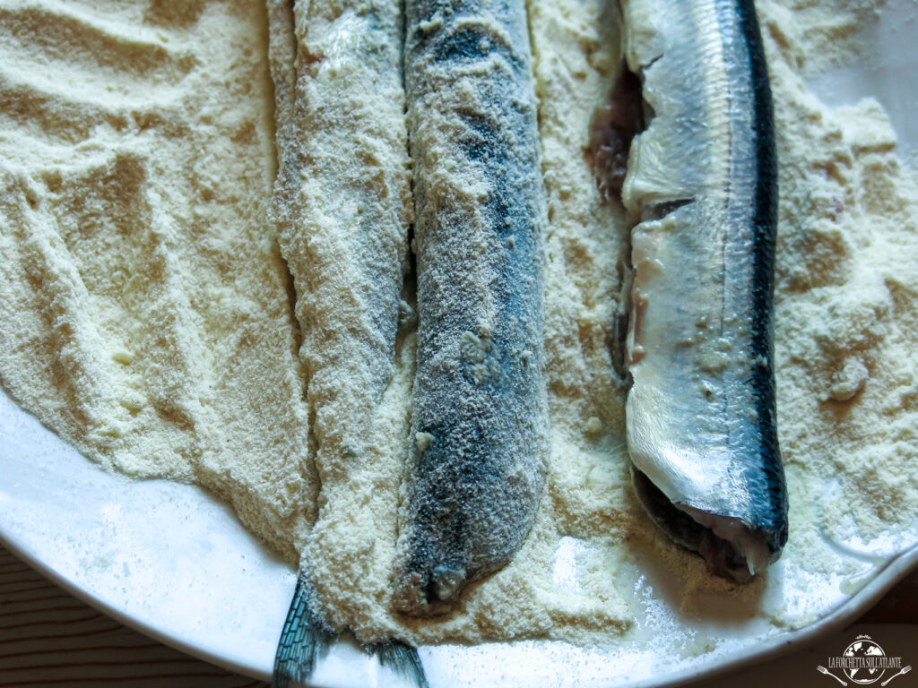 Costardelle fritte dorate e croccanti servite su un piatto con una spruzzata di limone, rappresentano un piatto tipico della cucina tradizionale calabrese e siciliana.

