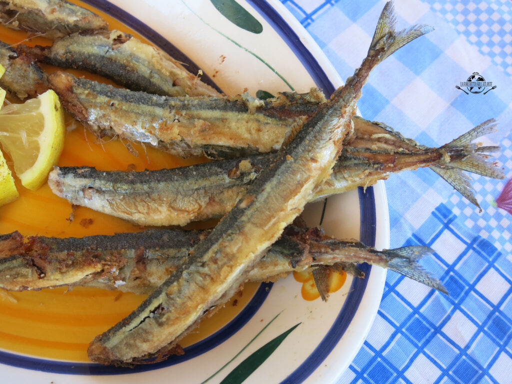 Costardelle fritte dorate e croccanti servite su un piatto con una spruzzata di limone, rappresentano un piatto tipico della cucina tradizionale calabrese e siciliana.

