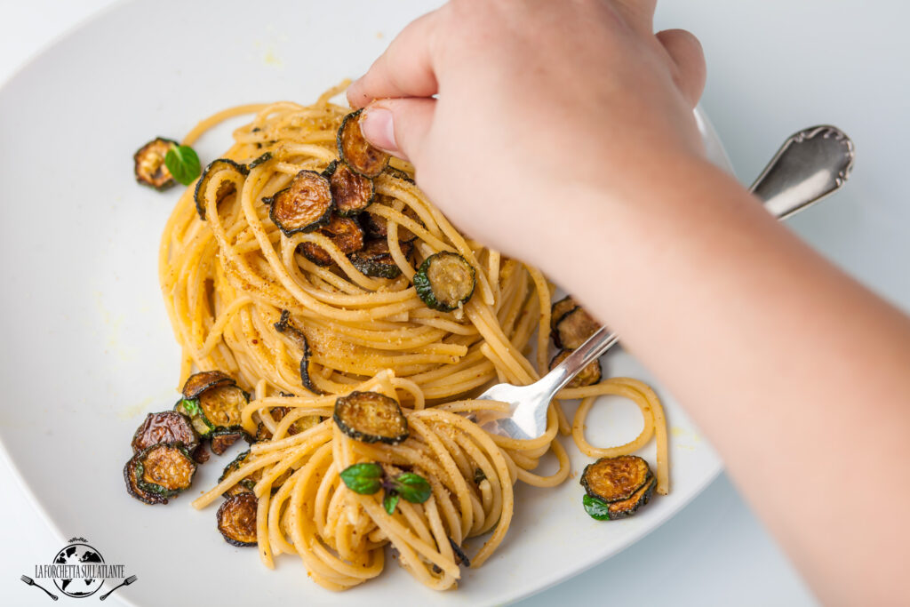 Spaghetti alla Nerano serviti con zucchine fritte e Provolone del Monaco, piatto tipico della Costiera Amalfitana.