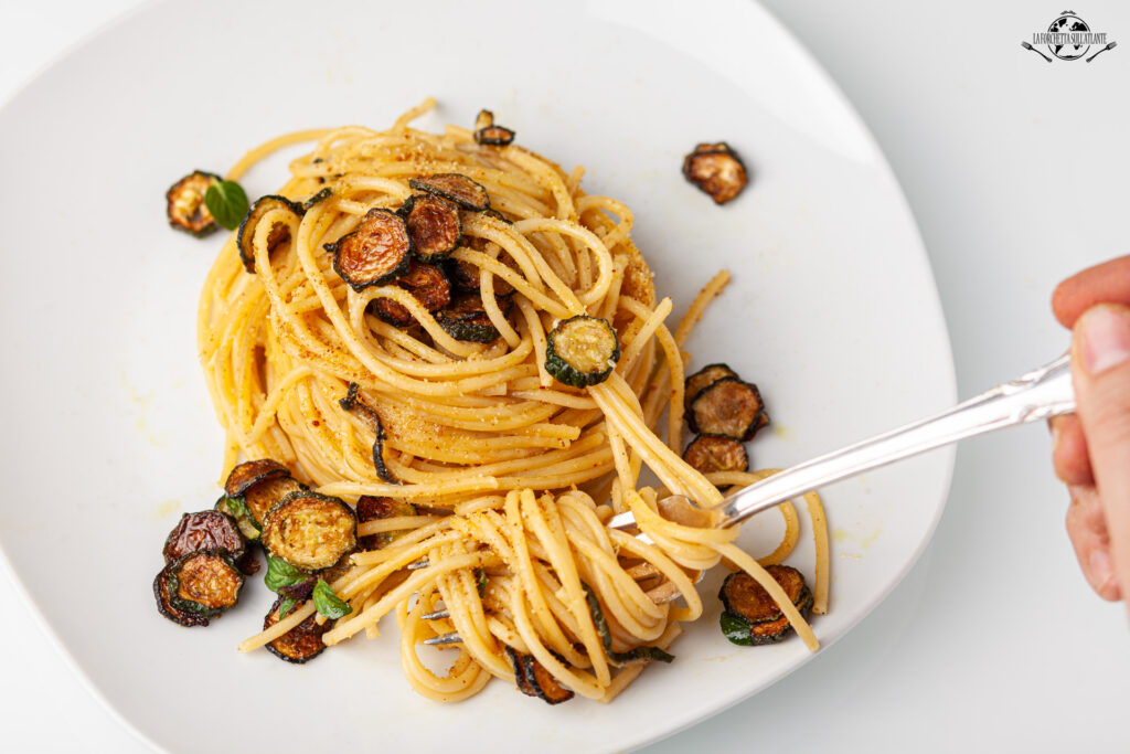 Spaghetti alla Nerano serviti con zucchine fritte e Provolone del Monaco, piatto tipico della Costiera Amalfitana.