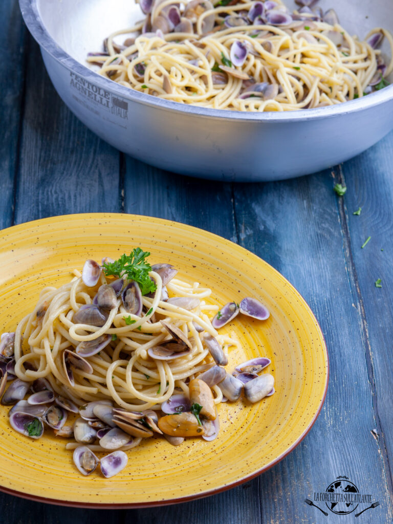 Piatto di Spaghettoni con telline e prezzemolo su sfondo di legno, un piatto semplice e saporito, perfetto per celebrare la fine dell'estate.

