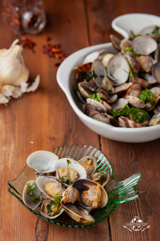 Sauté di vongole veraci servito con bicchiere di vino bianco fresco, pronto per essere gustato.